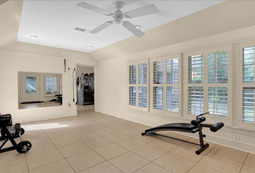 Spacious room featuring large windows with plantation shutters, tile flooring, recessed lighting, and a ceiling fan.  SO nice!