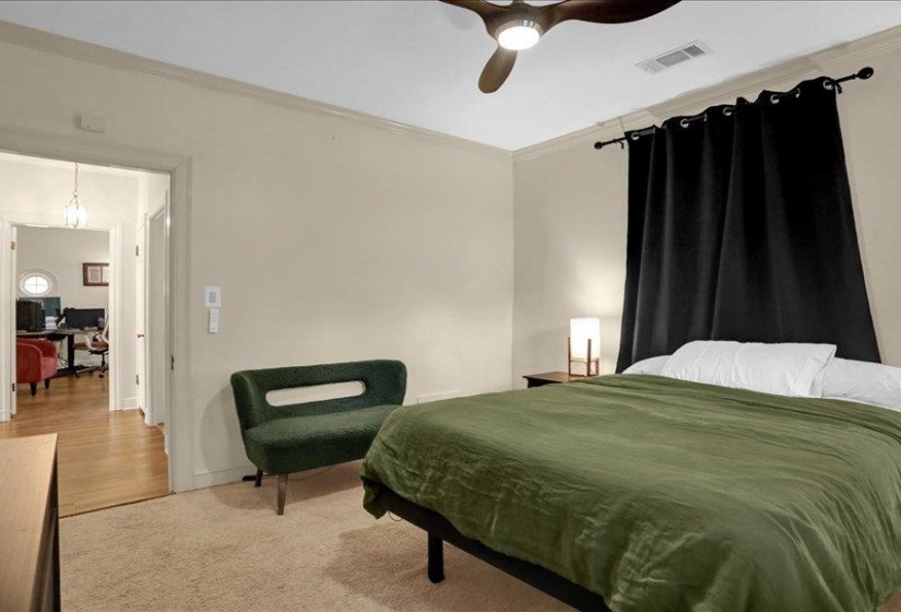 Carpeted bedroom featuring neutral wall paint, crown molding, and a ceiling fan with integrated lighting