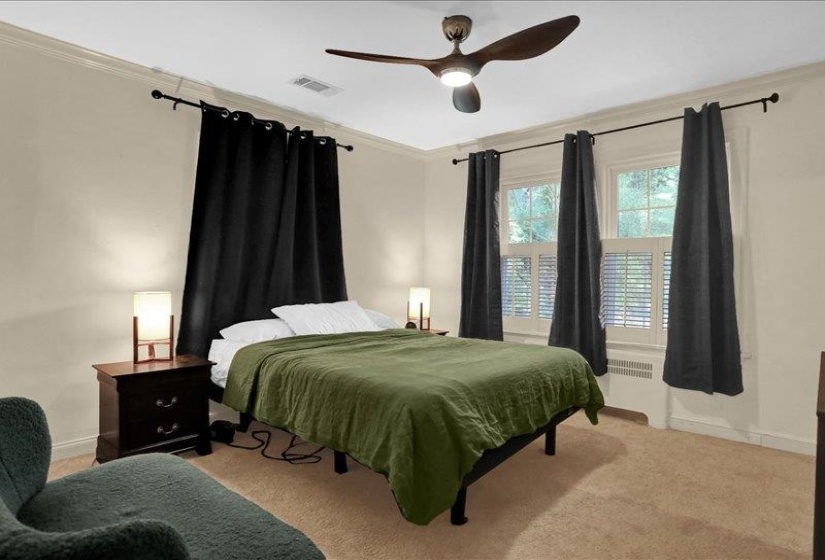Carpeted room featuring a ceiling fan with integrated lighting, crown molding, and two windows with white plantation shutters
