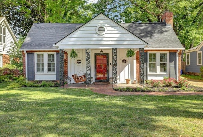 Charming, traditional, cottage-style home featuring a red brick and white siding facade.