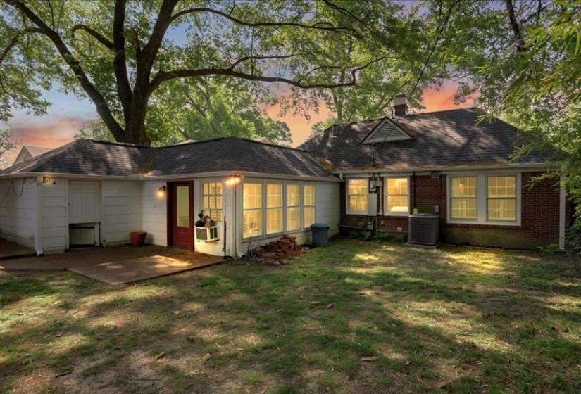 Rear exterior featuring a concrete patio, white painted siding, and brick facade....and a dutch door / doggie door leading into the garage.  Cute.