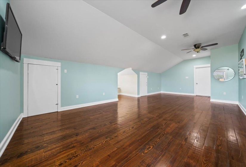 Spacious room above garage featuring wood flooring.