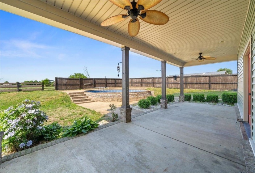 Expansive covered patio with concrete flooring and two ceiling fans