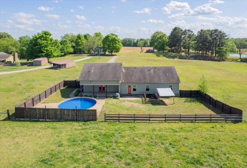 Rear exterior featuring a swimming pool with surrounding concrete patio and wood privacy fencing