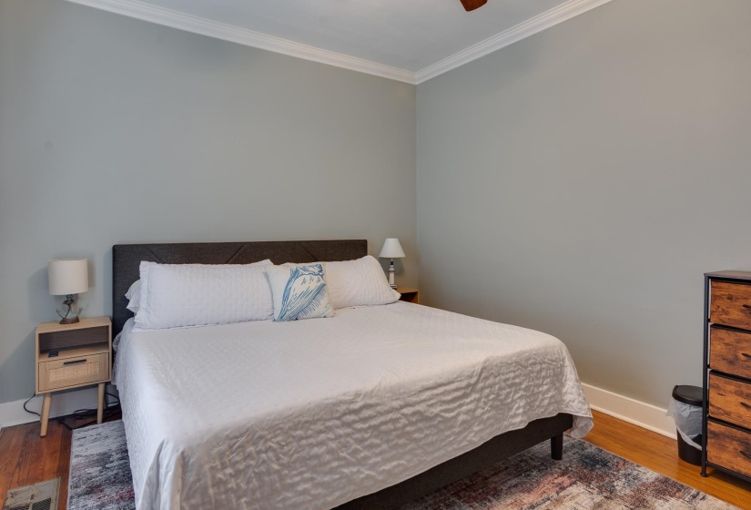 Bedroom featuring hardwood flooring, crown molding, a ceiling fan, and painted walls