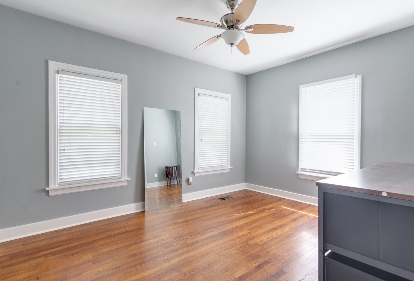 Spacious room featuring wood-finish flooring, light gray walls, and two large windows with blinds