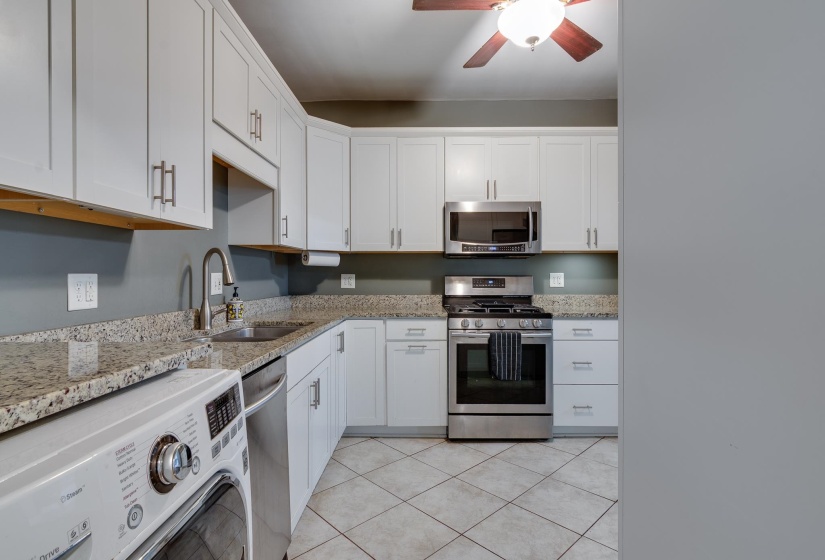 Kitchen featuring white cabinetry, granite countertops, stainless steel appliances, a ceiling fan, and diamond-patterned tile flooring
