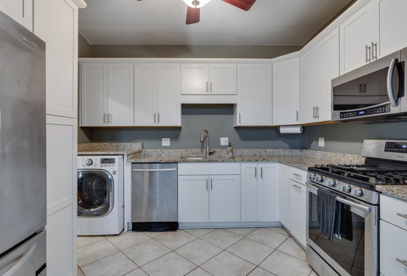 Kitchen featuring white cabinetry, stainless steel appliances, granite-style countertops, and tile flooring
