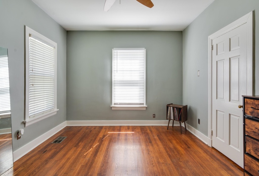 Bright room featuring wood-finish flooring, two windows with blinds, a ceiling fan, and painted walls