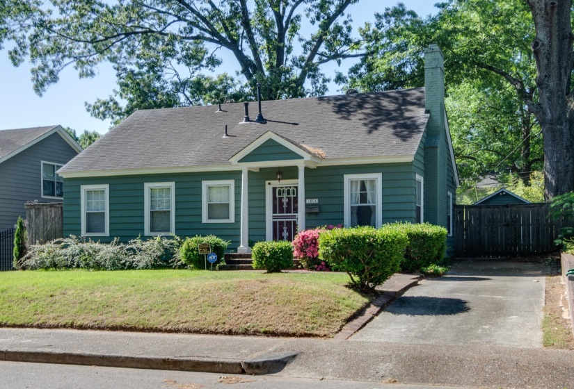 Green clapboard siding exterior with a dark shingle roof, featuring a covered front porch with white columns
