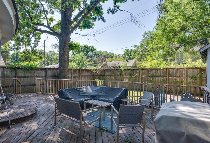 Spacious wood deck with perimeter wood railing, featuring a built-in circular platform, and backing to a privacy fence