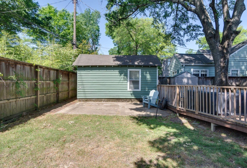 Expansive green space featuring a concrete patio, wood privacy fencing, and mature trees