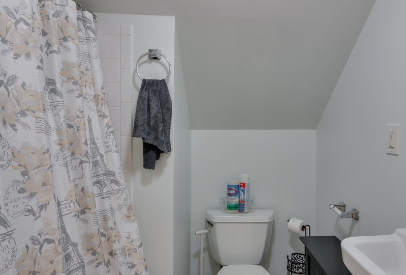 Bathroom featuring white wall tile, a white toilet, and a white sink basin