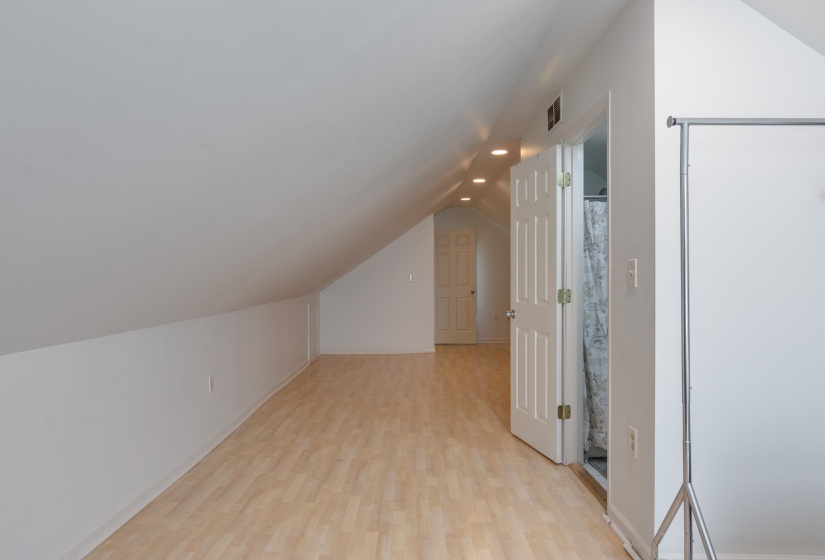 Attic space featuring wood-finish flooring, recessed lighting, and white paneled doors
