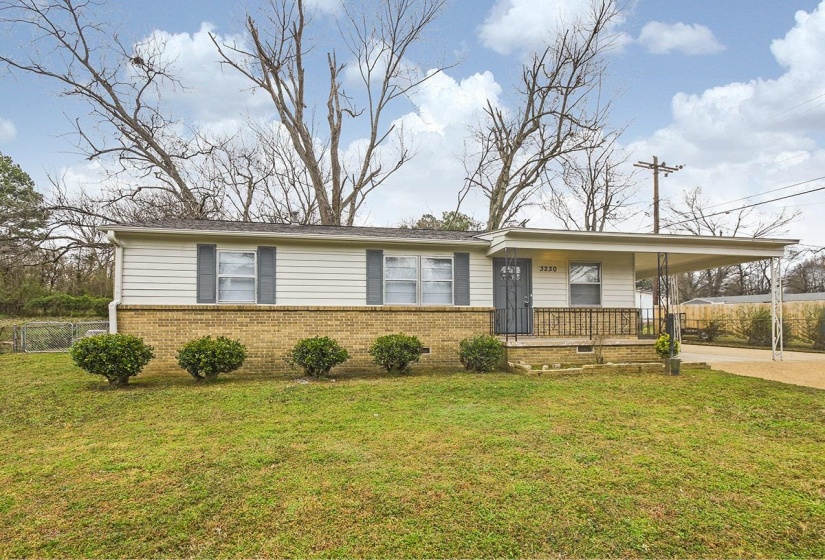 View of front of house featuring a porch, brick siding, concrete driveway, and a carport
