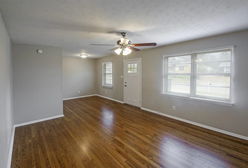 Unfurnished living room with dark wood-style flooring, a ceiling fan, and a textured ceiling