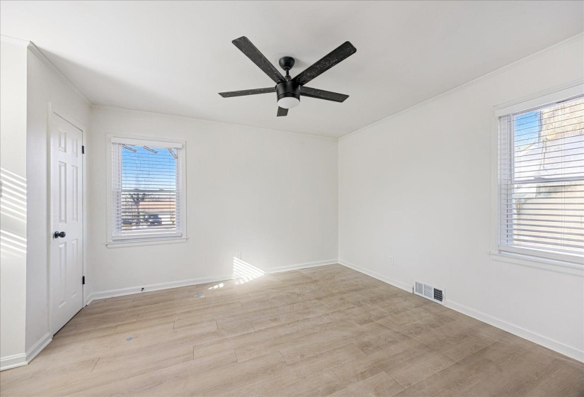 Room with light wood-finish flooring, white walls, and a black ceiling fan