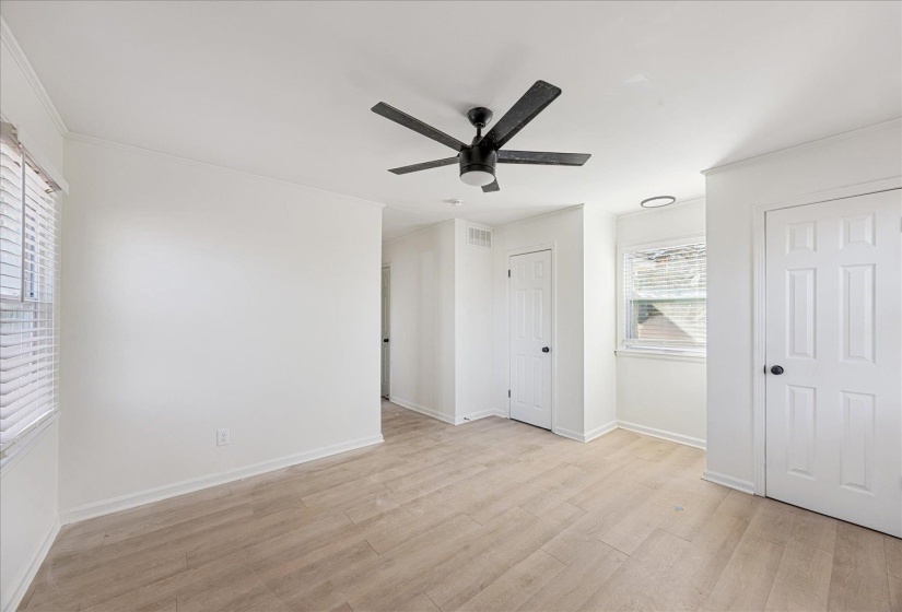 Spacious room featuring wood-finish flooring, a contemporary ceiling fan, and crisp white walls