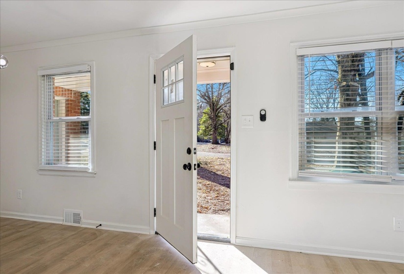 Entryway featuring a white paneled door with glass inserts, two large windows, wood-finish flooring, and white baseboards