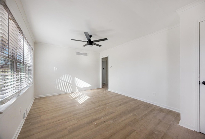 Room featuring wood-finish flooring, white walls, and crown molding