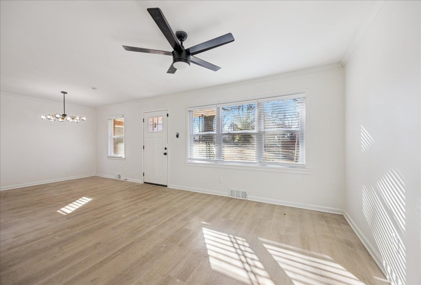 Bright interior space featuring light wood-finish flooring, white walls, and crown molding