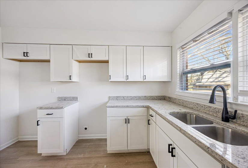 Kitchen with abundant white cabinetry, light-toned countertops, and wood-finish flooring