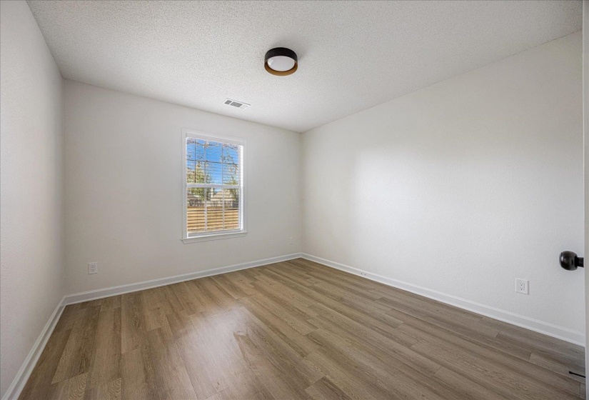 Room featuring wood-finish flooring, white walls, and a window with blinds