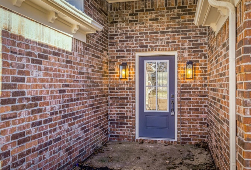 Brick exterior featuring a blue paneled door with multiple glass lites and white trim