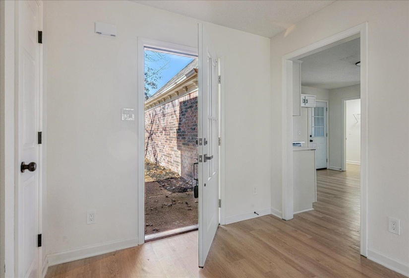 Entryway featuring light wood-finish flooring, white walls, and a white door with dark hardware