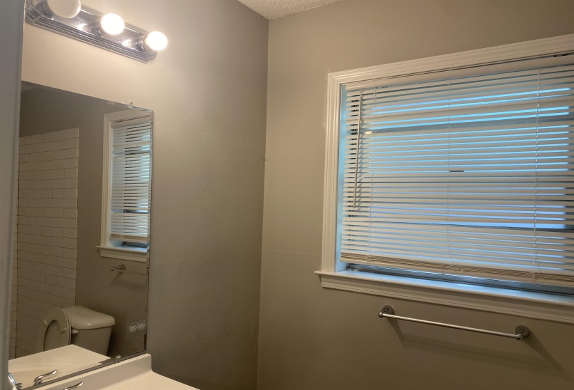 Bathroom featuring a window with white blinds, a chrome towel bar, and neutral wall tones
