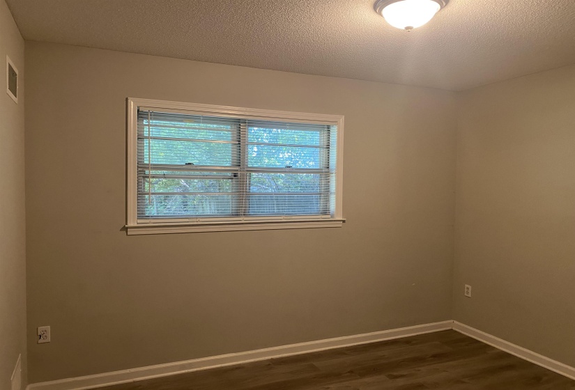 Interior room featuring neutral wall paint, wood-finish flooring, white baseboards, and a window with white trim and blinds