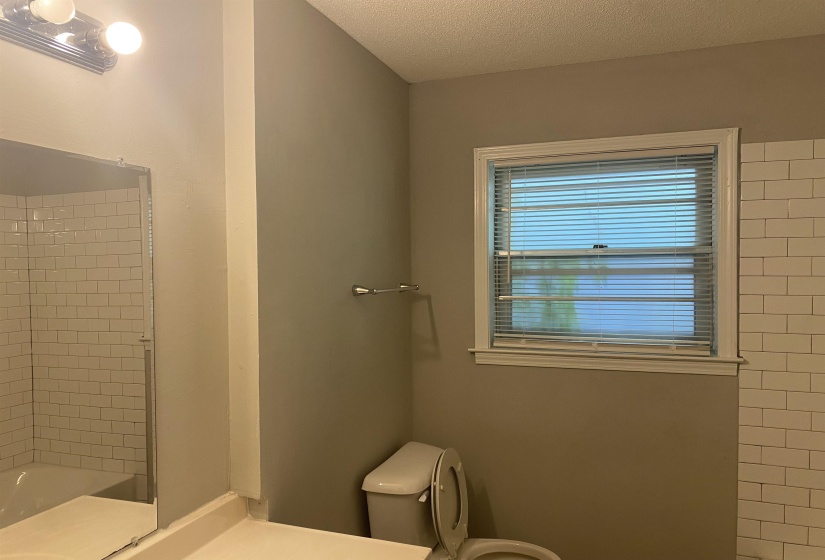 Bathroom featuring subway tile shower surround, a window with horizontal blinds, and a neutral wall color