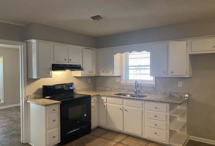 Kitchen featuring white cabinetry, granite-finish countertops, and tile flooring