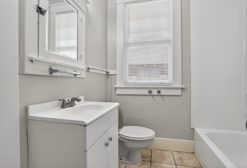 Bathroom featuring a white vanity with integrated sink, ceramic tile flooring, a window with blinds, and a white medicine cabinet