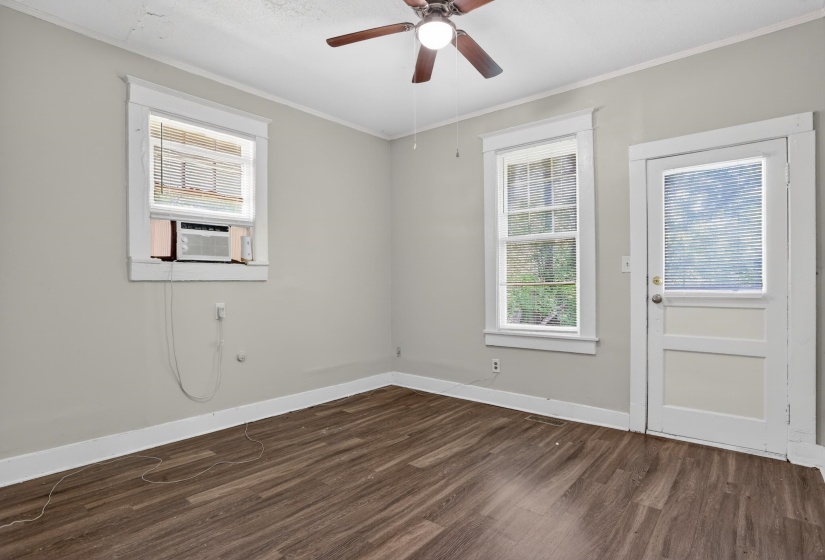 Room featuring wood-finish flooring, two windows with white trim, and a white paneled door