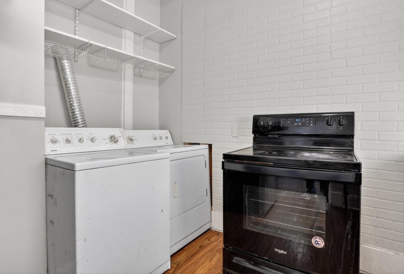 Dedicated laundry area featuring a white washing machine and dryer, complemented by overhead shelving for storage