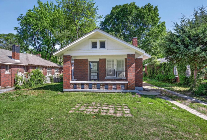 Brick facade home featuring a covered front porch with brick columns and a decorative half-wall