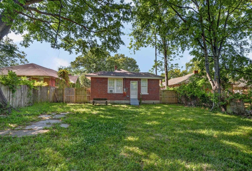 Expansive grassy backyard featuring a brick exterior and a privacy fence