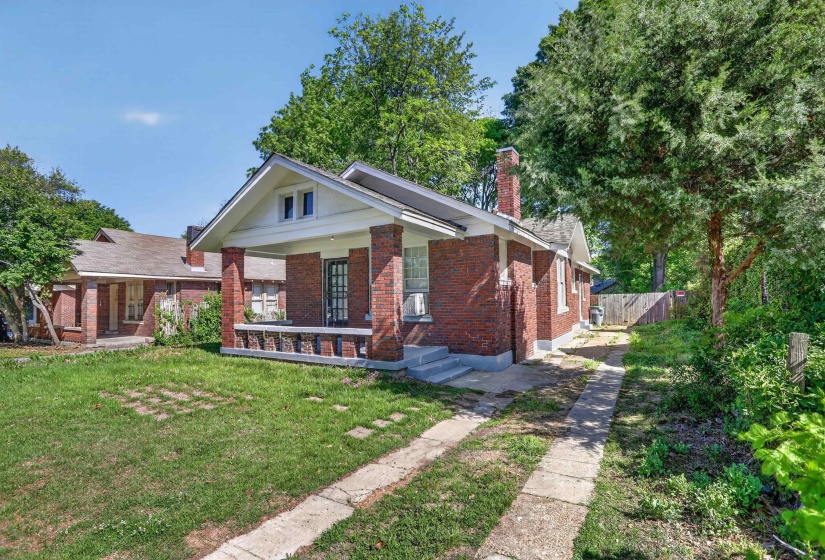Brick-clad bungalow featuring a covered front porch with brick columns and a decorative half-wall