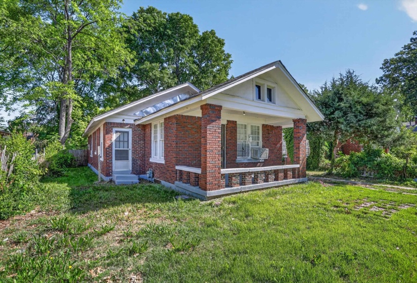 Brick exterior featuring a covered front porch with column supports and a decorative half-wall