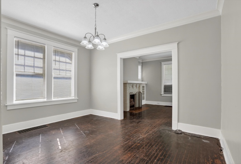 Bright room with dark wood-finish flooring, featuring a five-light chandelier, white trim, and crown molding