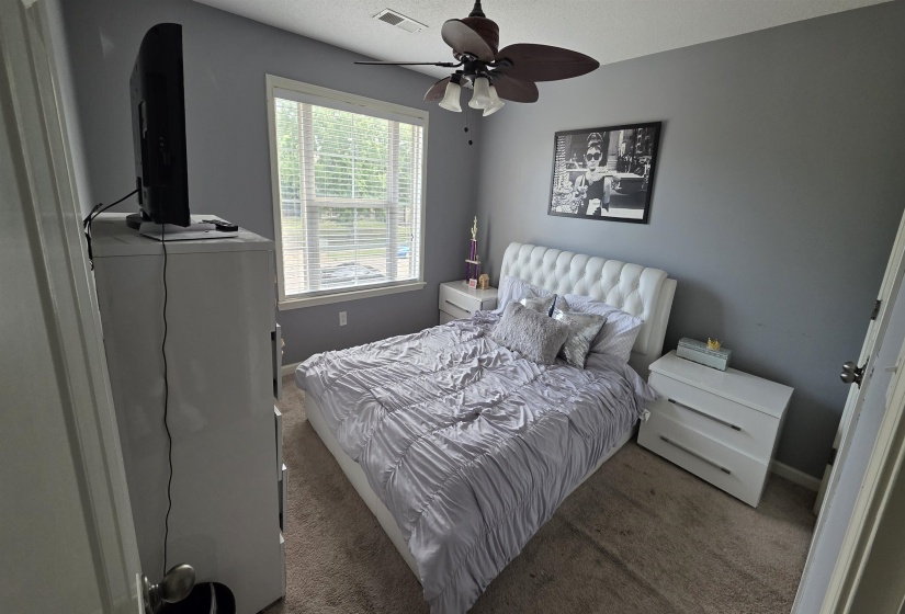Carpeted room with a ceiling fan, a window featuring horizontal blinds, and neutral-toned walls