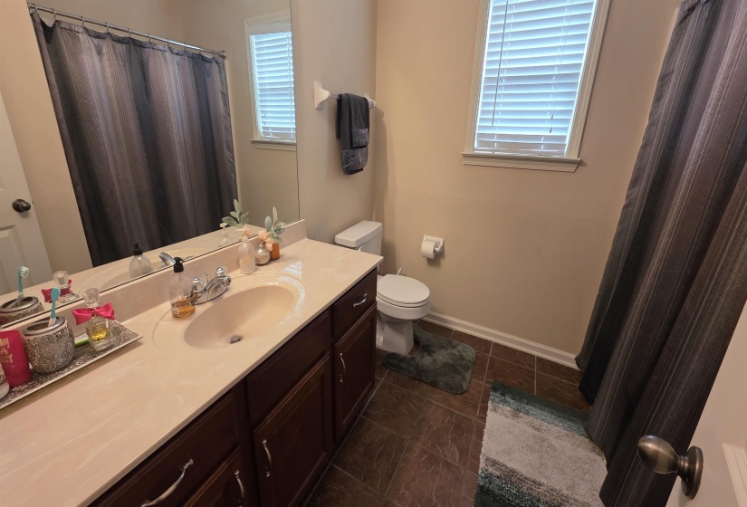 Bathroom featuring a vanity with a light-colored countertop, an integrated sink, dark wood-finish cabinetry, and a large wall-mounted mirror