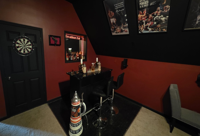 Dedicated entertainment area featuring a built-in bar, black trim, and a dartboard
