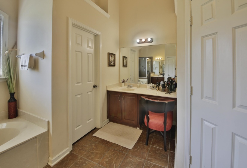 Bathroom vanity featuring a light-colored countertop, integrated sink, wood-finish cabinetry, and an expansive mirror