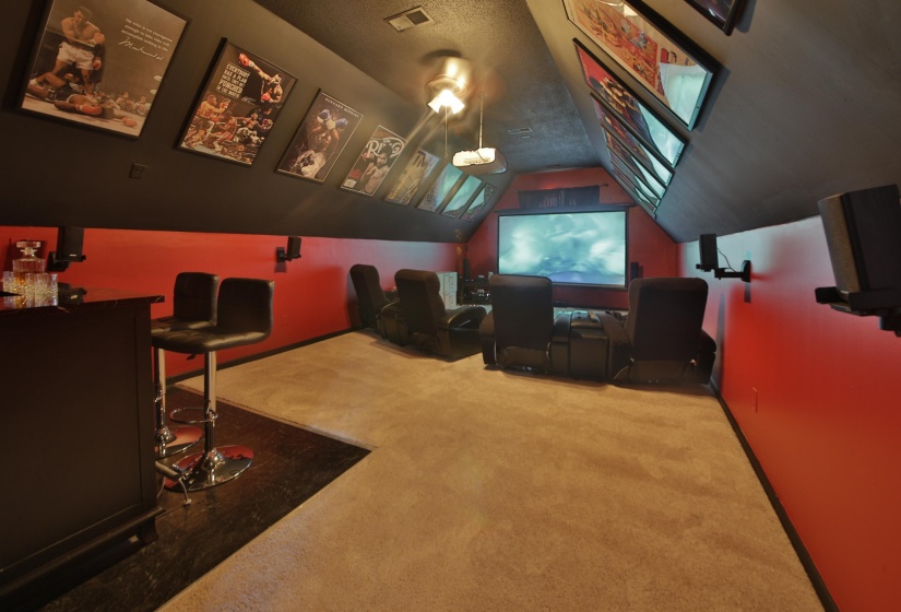 Media room with sloped ceilings and recessed lighting