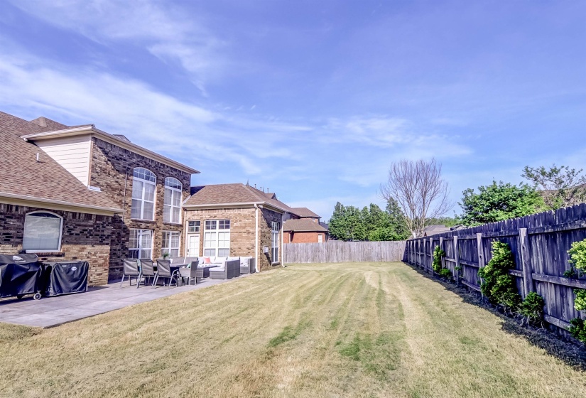 Brick exterior featuring a spacious patio with multiple access points, a private fenced yard, and abundant natural light through arched and rectangular windows