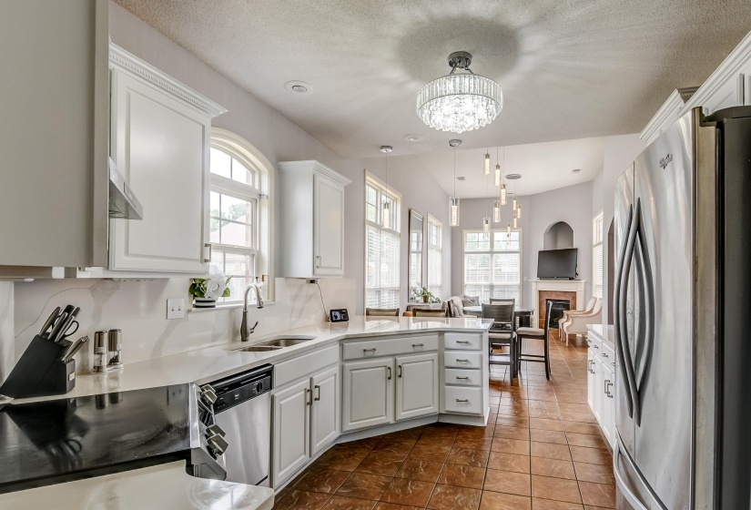 Open-concept kitchen featuring white cabinetry, light countertops, and stainless steel appliances