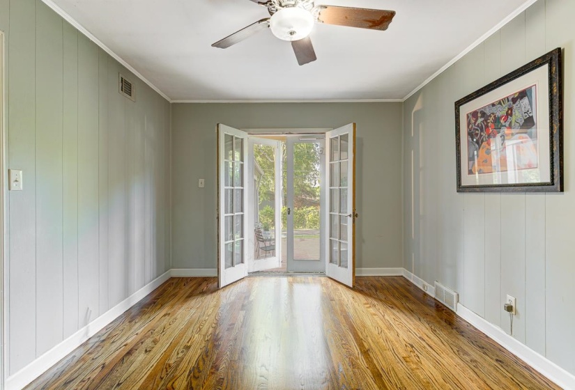 Spacious room featuring rich wood-finish flooring, light green paneled walls, and white trim