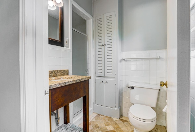 Bathroom featuring a wood-finish vanity with a stone countertop, an integrated sink, and a framed mirror